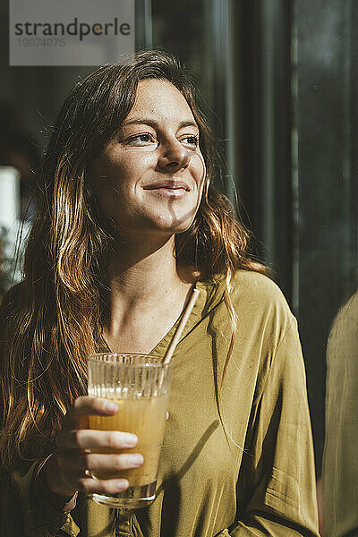 Lächelnde junge Frau mit einem Glas Saft