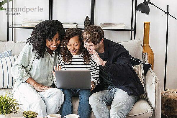 Eltern sitzen auf dem Sofa und surfen mit ihrer Tochter am Laptop im Internet