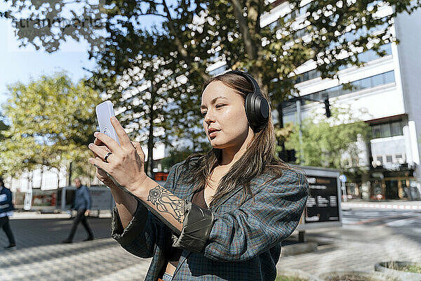 Frau fotografiert mit Smartphone an sonnigem Tag