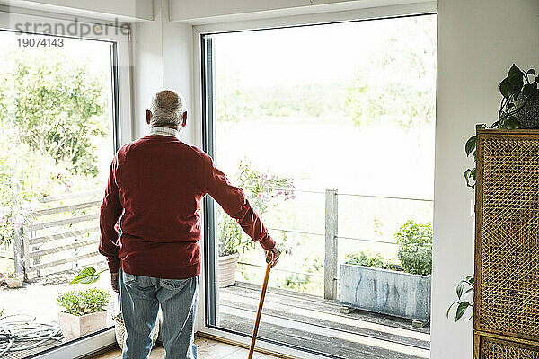 Nachdenklicher älterer Mann steht vor dem Fenster