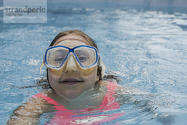 Girl wearing swimming goggles in pool