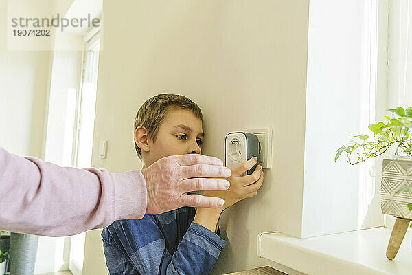 Großvater hilft Enkel bei der Installation des Timers in der Steckdose an der Wand