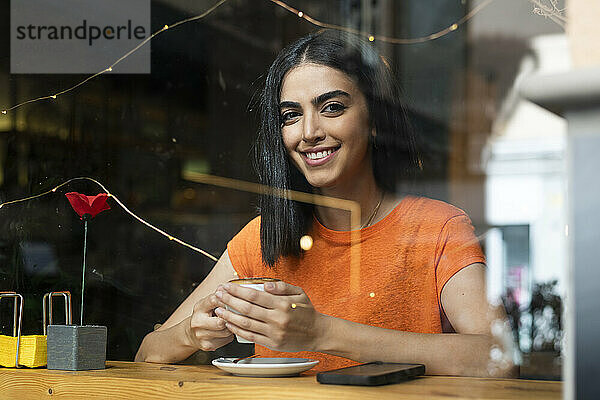 Lächelnde junge Frau genießt Kaffee im Café