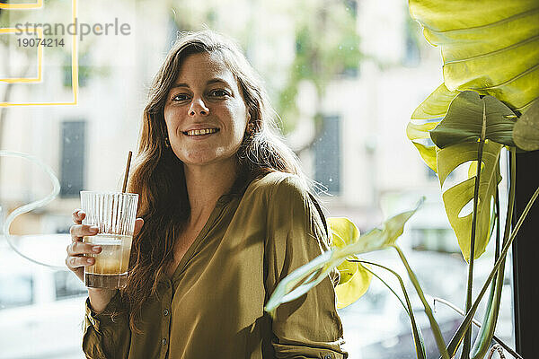 Lächelnde Frau mit einem Glas Saft im Café