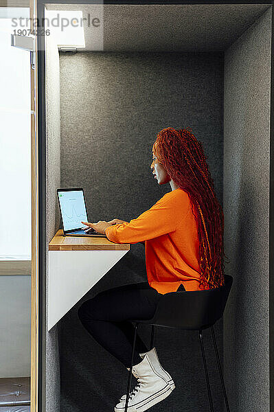 Geschäftsfrau arbeitet am Laptop und sitzt auf einem Stuhl im Büro