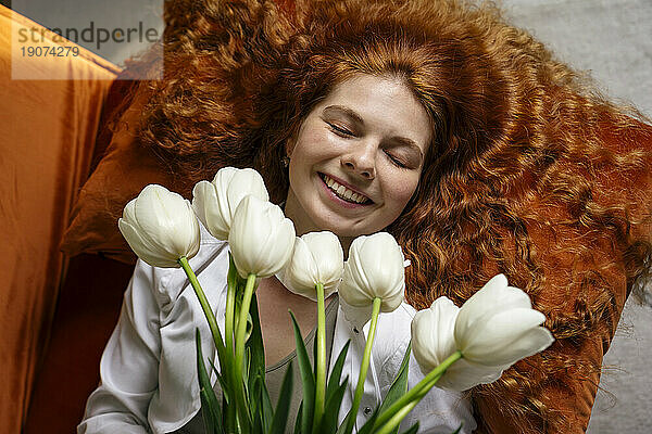 Young redhead woman holding bunch of tulip flowers at home