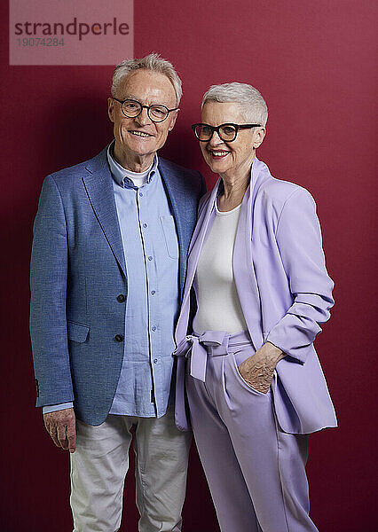 Porträt eines selbstbewussten Seniorenpaares vor violettem Hintergrund
