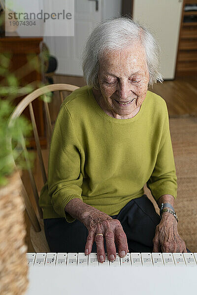 Elderly smiling woman playing piano at home
