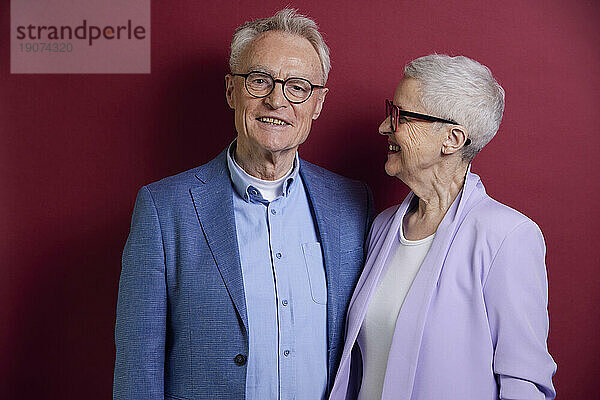 Ältere Frau blickt Mann vor violettem Hintergrund an