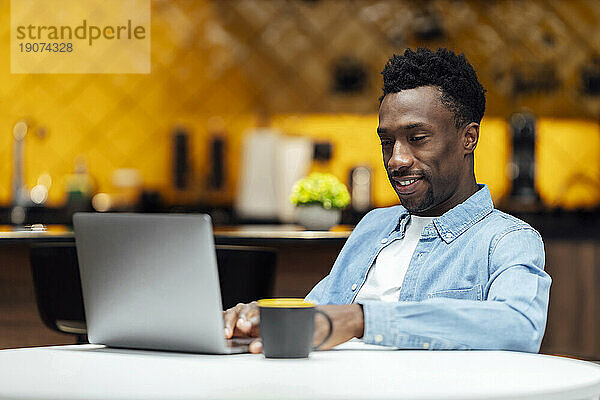 Lächelnder Geschäftsmann mit Laptop am Arbeitsplatz