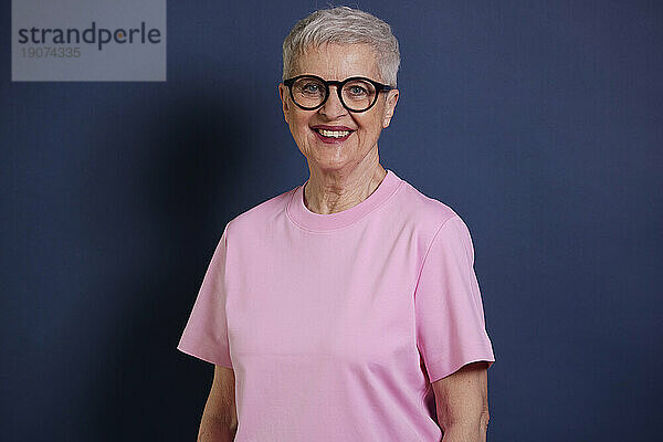 Porträt einer lächelnden älteren Frau vor blauem Hintergrund