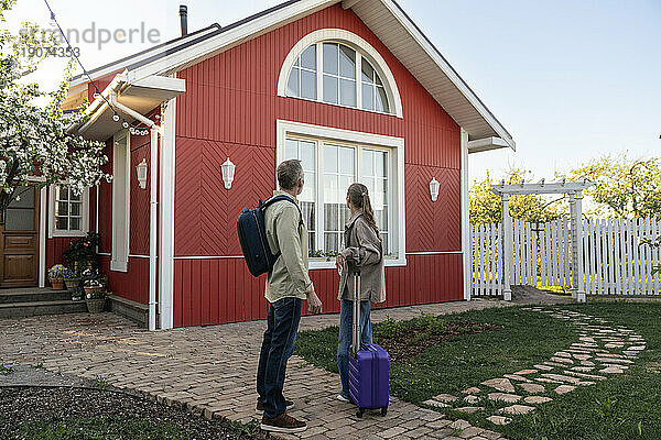 Couple with luggage looking at house