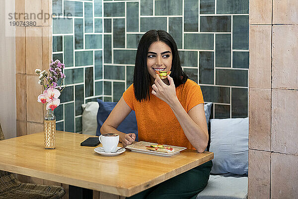 Junge Frau genießt Snacks und Kaffee im Café