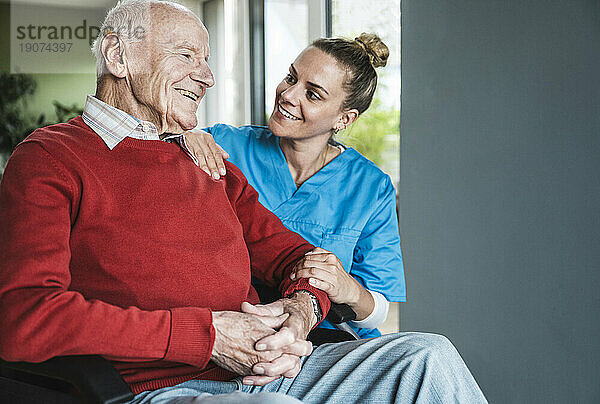 Glückliche Krankenschwester  die sich um den älteren Mann zu Hause kümmert und ihn unterstützt