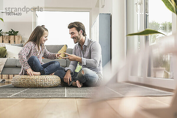 Junger Mann und kleines Mädchen sitzen zu Hause und spielen Papierschere und Stein