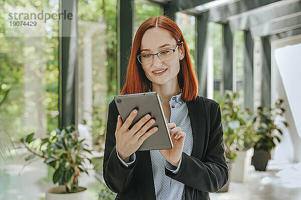 Lächelnde Geschäftsfrau nutzt Tablet-PC im Büro