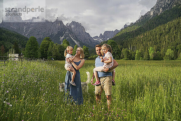 Vater und Mutter mit Töchtern stehen vor Bergen