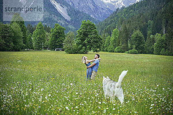 Romantic couple standing on grass in front of mountains