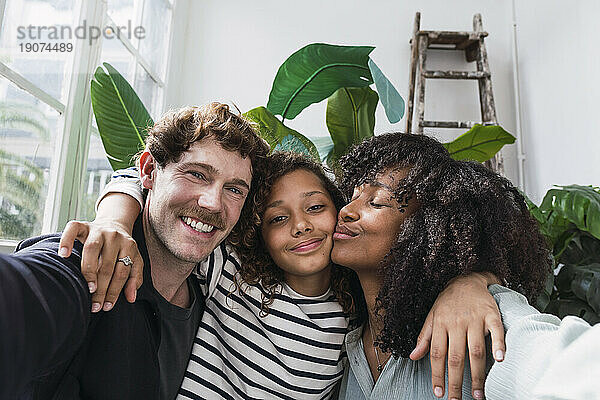 Eine fröhliche Familie hält einen gemeinsamen Moment in einem Wintergarten mit einem lustigen Selfie fest