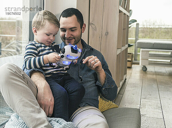 Father and son playing with a toy robot at home