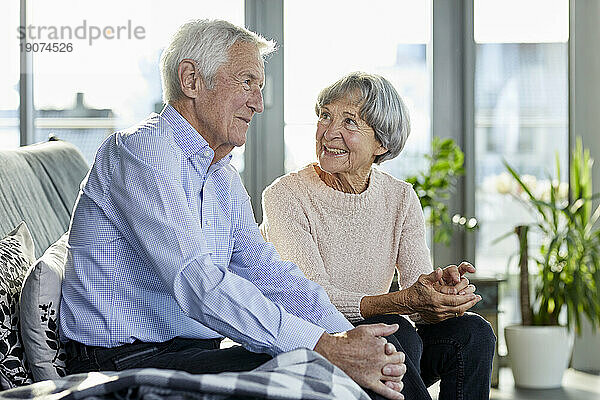 Älteres Paar sitzt auf der Couch und redet miteinander