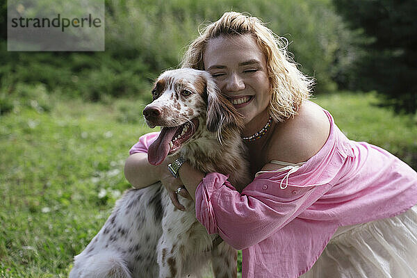 Glückliche Frau umarmt Hund im Park