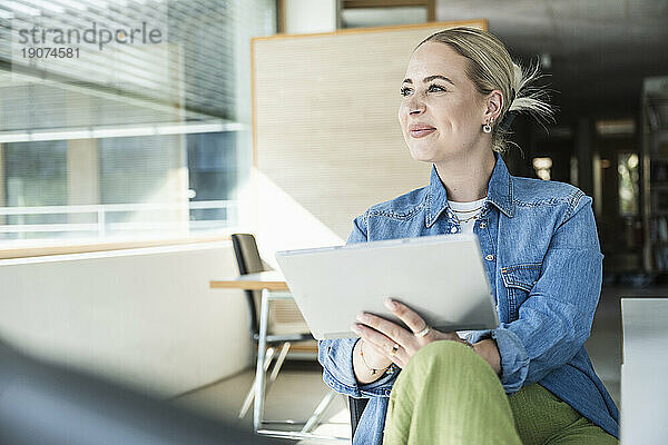 Lächelnde Geschäftsfrau sitzt mit Tablet-PC