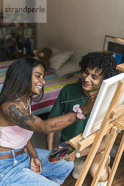 Glückliches Paar malt zu Hause auf Leinwand