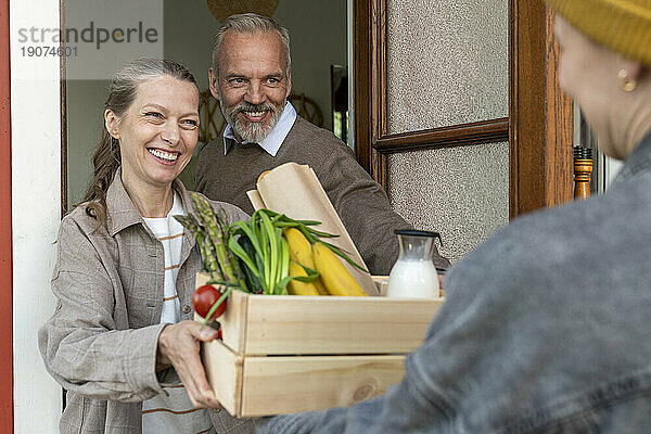 Glückliches älteres Paar  das Lebensmittel per Hauslieferung erhält