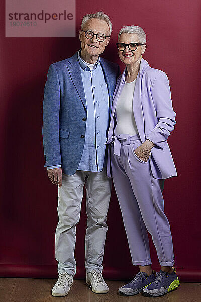 Porträt eines selbstbewussten Seniorenpaares vor violettem Hintergrund