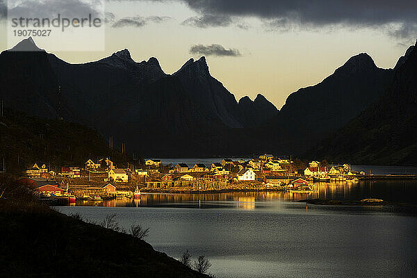 Silhouetten von Bergen  die das Märchendorf am Fjord im Morgengrauen umrahmen  Reine Bay  Lofoten  Nordland  Norwegen  Skandinavien  Europa