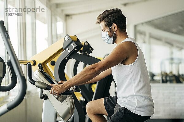 Seitenansicht Mann Fitnessstudio arbeiten mit medizinischen Maske