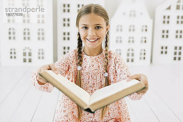 Hübsches glückliches Mädchen posiert mit Buch