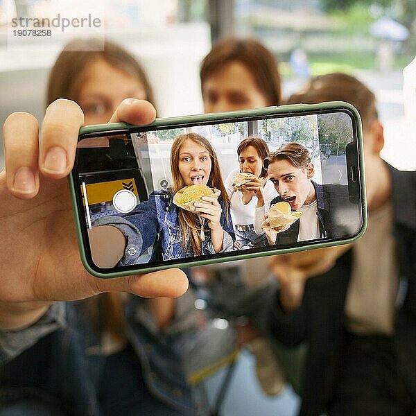 Gruppe von Freunden  die zusammen ein Selfie machen  während sie Fast Food essen