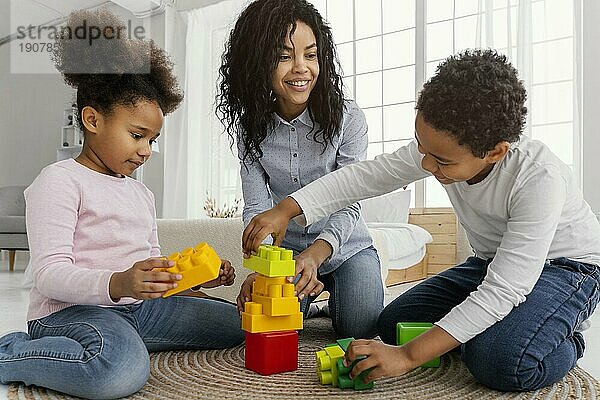 Lächelnde Mutter  die zu Hause mit ihren Kindern spielt
