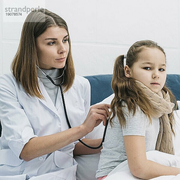 Porträt einer Ärztin  die ein erkältetes Mädchen untersucht