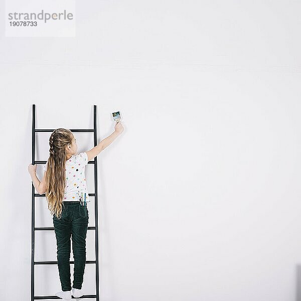 Kleines Mädchen Leiter Malerei Wand