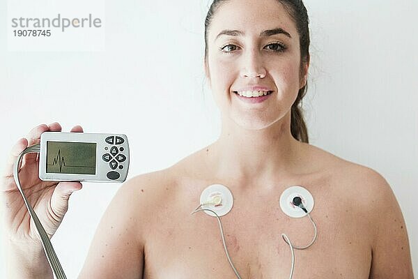Frau mit Elektroden  die einen Monitor mit Kardiogramm hält