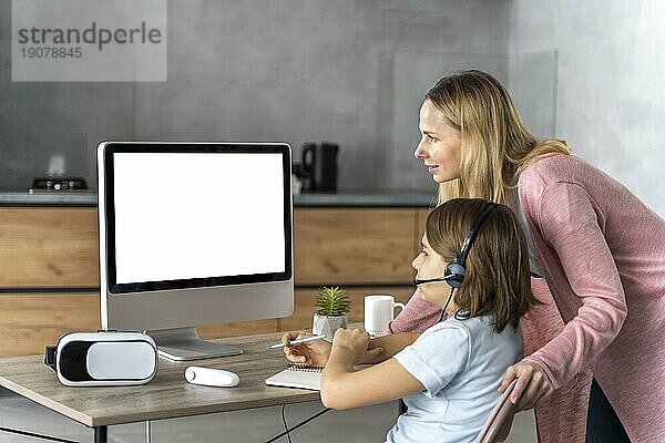 Mädchen mit Headset beim Online Lernen mit Mutter an ihrer Seite