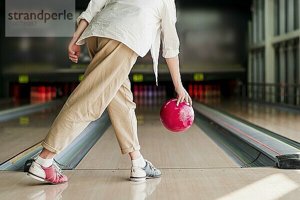 Person wirft rote Bowlingkugel