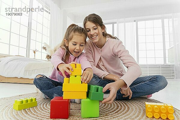 Vorderansicht zwei Schwestern spielen zu Hause Spielzeug