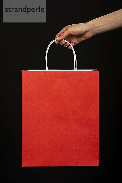 Close up Hand hält rote Einkaufstasche schwarzem Hintergrund