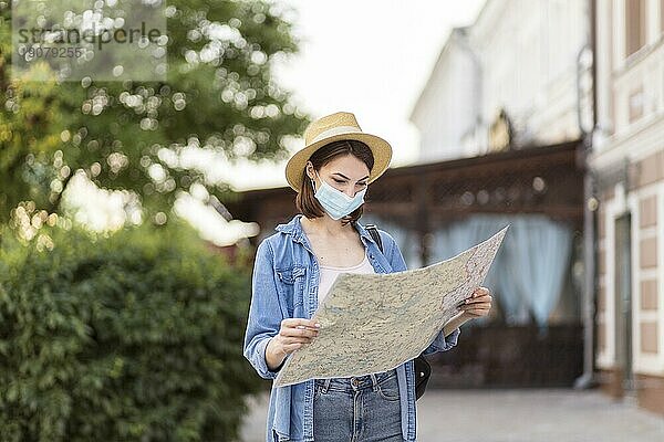Reisender mit Hut und medizinischer Maske  der die Karte kontrolliert