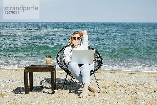 Frontansicht Frau mit Laptop arbeiten Strand mit Tasse Kaffee