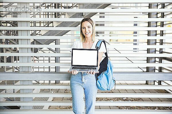 Gut gelaunte Frau zeigt Laptop Kamera