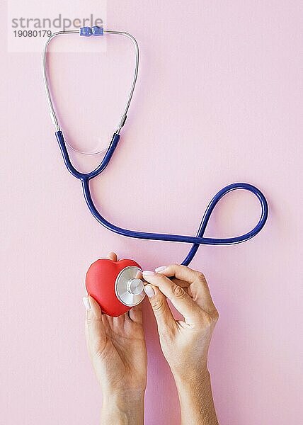 Draufsicht Hände  die das Herz mit einem Stethoskop prüfen
