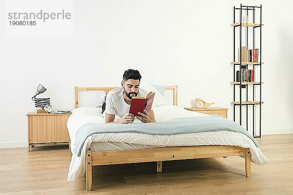 Mann liegend Bett lesend Buch Schlafzimmer