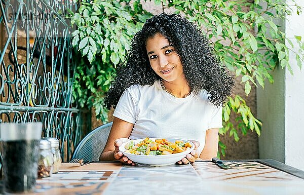 Portrait eines lächelnden Mädchens  das einen Caesarsalat isst. Konzept der gesunden Ernährung und gesundes Leben  Schönes Mädchen sitzt und hält einen Caesarsalat