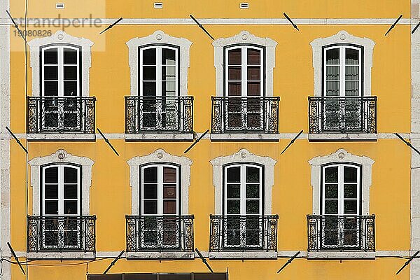 Traditionelles Gebäude mit gelber Fassade und hohen Fenstern mit Balkonen in Lissabon  Portugal  Europa