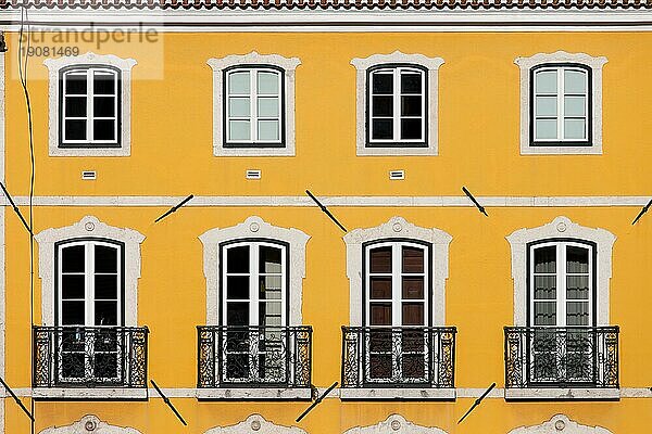 Traditionelles Haus mit gelber Fassade und hohen Fenstern mit Balkonen in Lissabon  Portugal  Europa